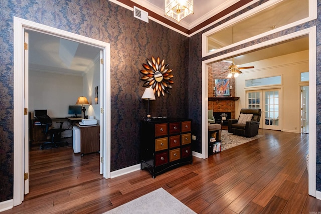 interior space featuring crown molding, french doors, a brick fireplace, and hardwood / wood-style flooring