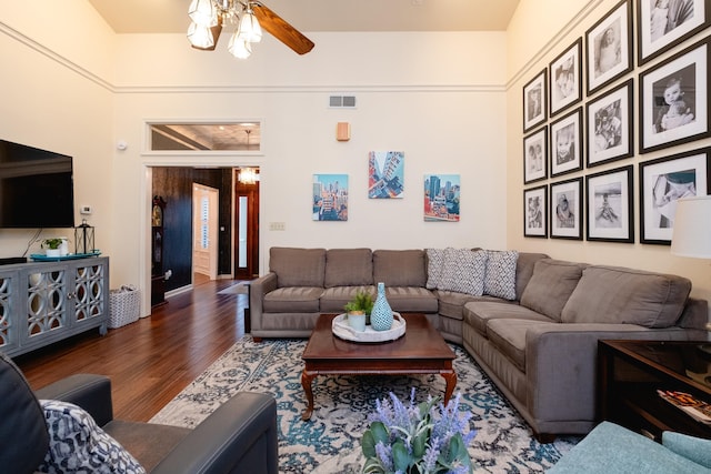 living room featuring ceiling fan, dark hardwood / wood-style flooring, and a towering ceiling