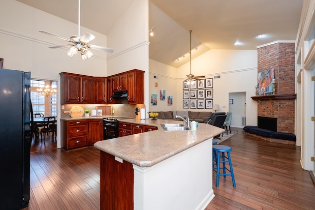 kitchen featuring ceiling fan with notable chandelier, black appliances, sink, a breakfast bar area, and kitchen peninsula