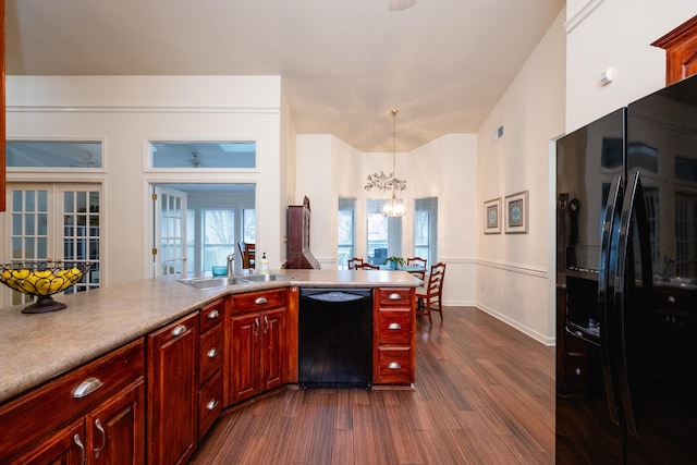 kitchen with pendant lighting, sink, a notable chandelier, black appliances, and dark hardwood / wood-style flooring