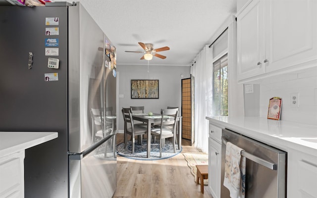 kitchen with tasteful backsplash, appliances with stainless steel finishes, a textured ceiling, and white cabinets