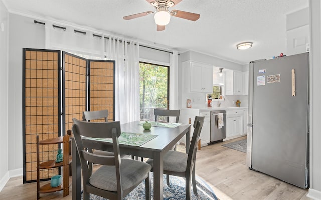 dining room with ceiling fan, light hardwood / wood-style floors, sink, and a textured ceiling