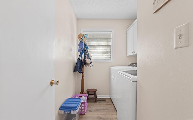 laundry area with cabinets, a textured ceiling, washer and clothes dryer, and light hardwood / wood-style flooring