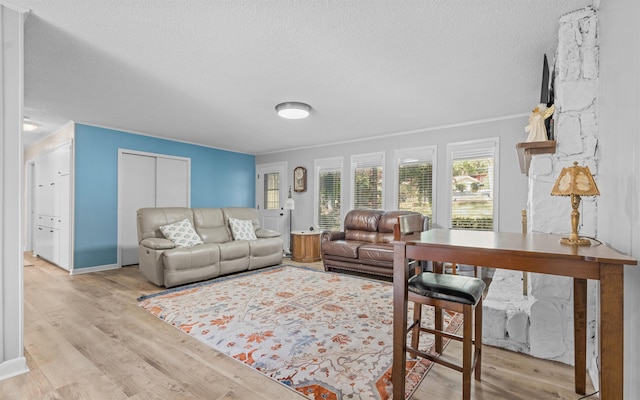 living room featuring ornamental molding, a textured ceiling, and light wood-type flooring