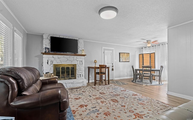 living room featuring hardwood / wood-style floors, crown molding, a fireplace, and ceiling fan