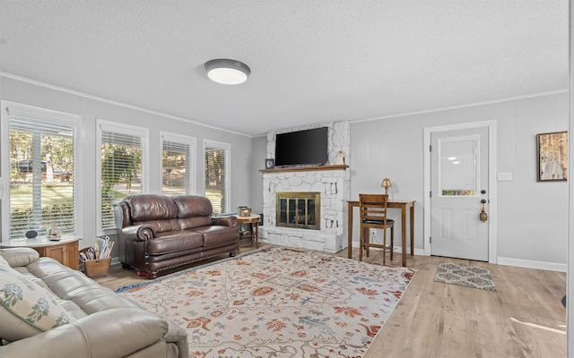 living room featuring ornamental molding, a stone fireplace, hardwood / wood-style floors, and a textured ceiling