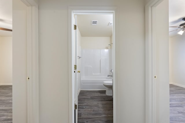 bathroom featuring ceiling fan, wood-type flooring, toilet, and shower / bathing tub combination