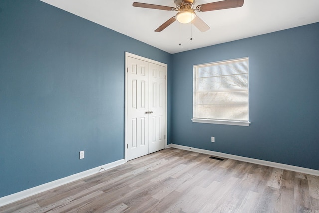 unfurnished bedroom with light hardwood / wood-style flooring, a closet, and ceiling fan