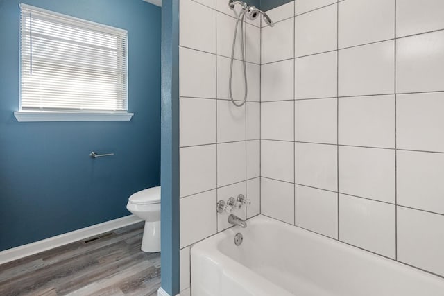 bathroom featuring hardwood / wood-style flooring, tiled shower / bath, and toilet