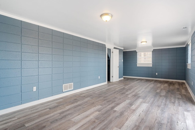 spare room featuring wood-type flooring and tile walls