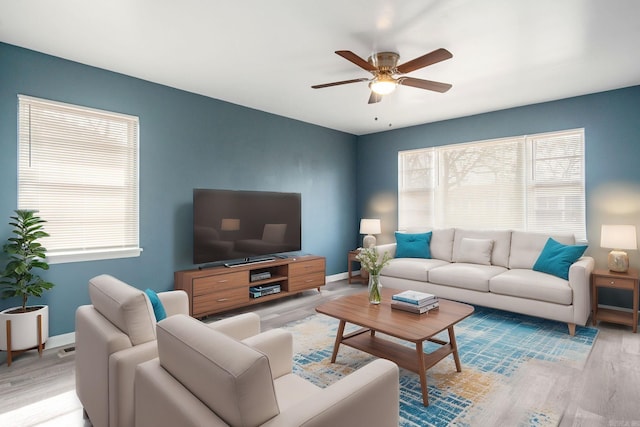 living room with ceiling fan, light wood-type flooring, and a wealth of natural light