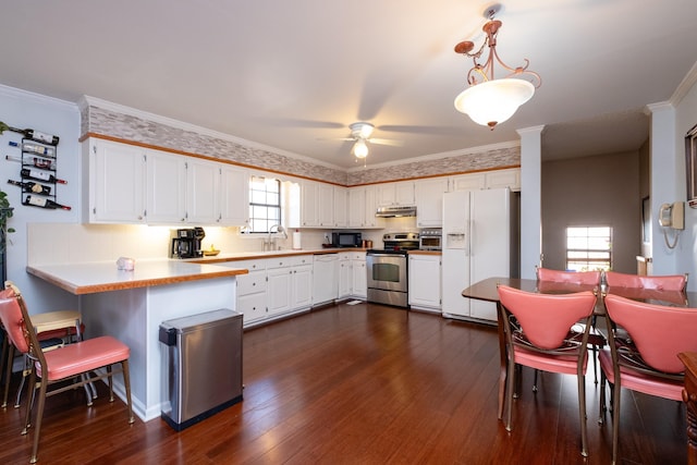 kitchen with dark wood-type flooring, decorative light fixtures, kitchen peninsula, white appliances, and white cabinets