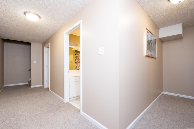 hallway with light carpet and a textured ceiling