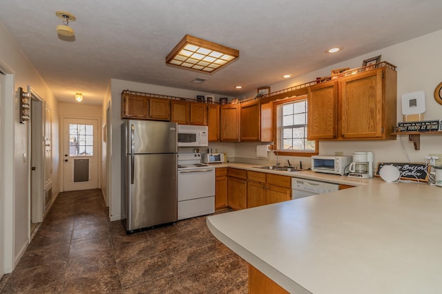 kitchen with white appliances, kitchen peninsula, and sink