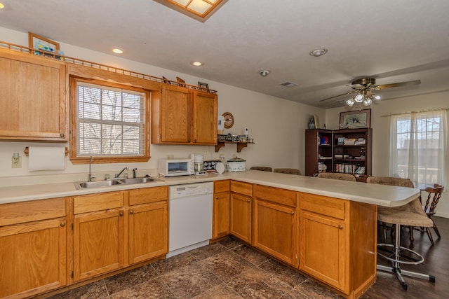 kitchen featuring white appliances, a breakfast bar area, kitchen peninsula, and a wealth of natural light