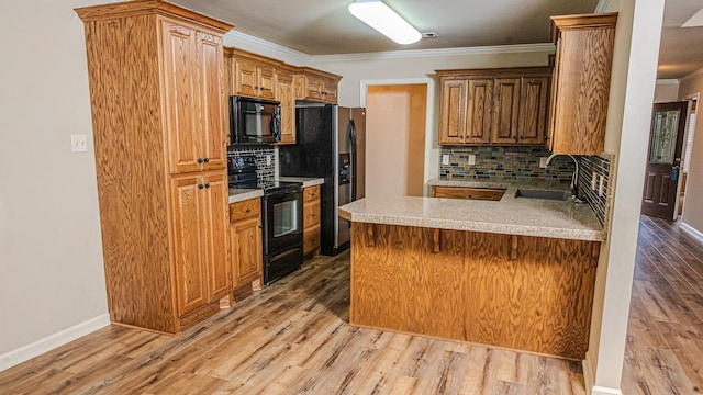 kitchen with sink, crown molding, light hardwood / wood-style flooring, kitchen peninsula, and black appliances