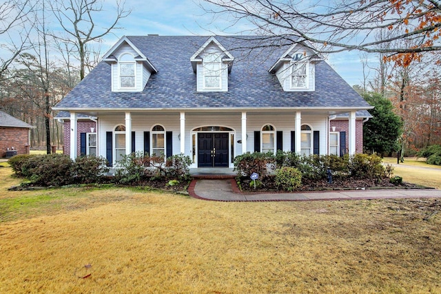 new england style home featuring a front lawn and covered porch