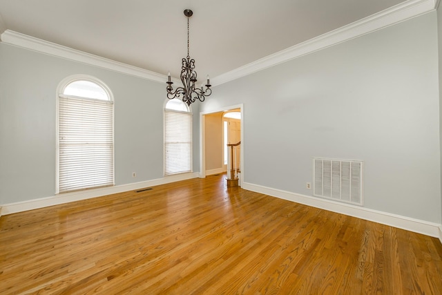 spare room with ornamental molding, an inviting chandelier, and light hardwood / wood-style flooring