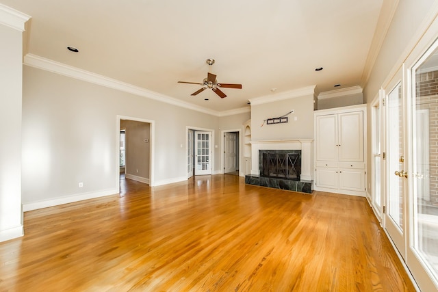 unfurnished living room with ceiling fan, ornamental molding, a premium fireplace, and light hardwood / wood-style floors