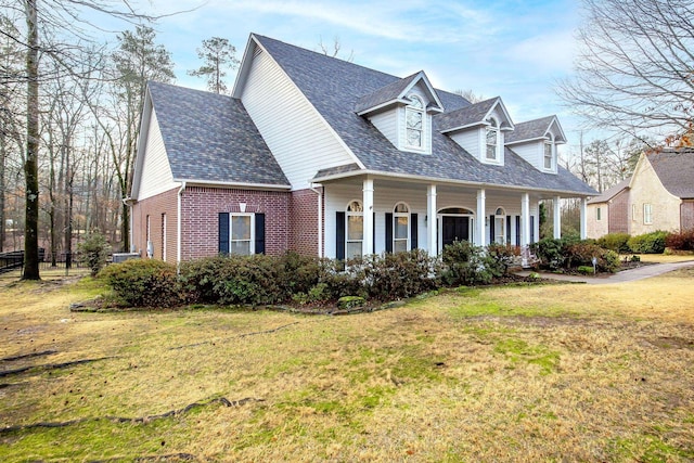 cape cod home with a front yard and covered porch