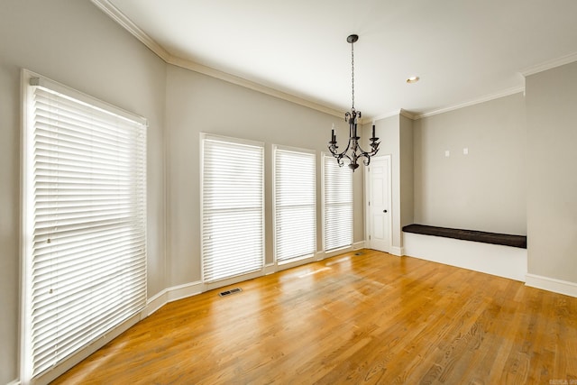 unfurnished dining area with hardwood / wood-style flooring, ornamental molding, and an inviting chandelier