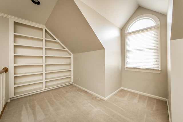 additional living space featuring built in features, vaulted ceiling, and light colored carpet