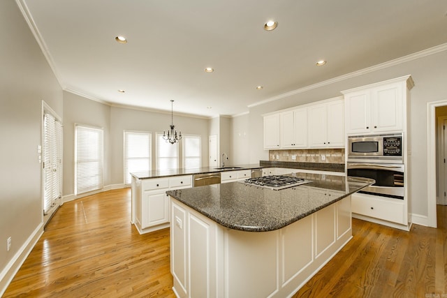 kitchen featuring sink, stainless steel appliances, white cabinets, a kitchen island, and kitchen peninsula