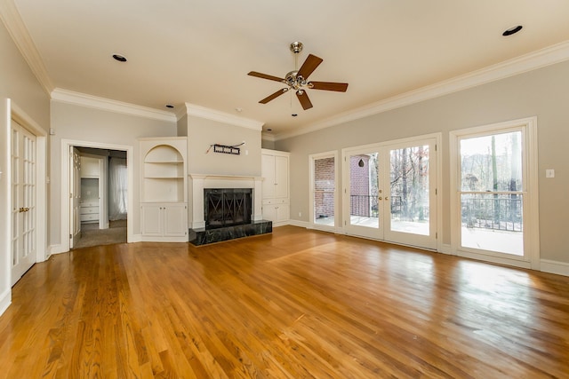 unfurnished living room featuring french doors, ceiling fan, a high end fireplace, crown molding, and light hardwood / wood-style flooring