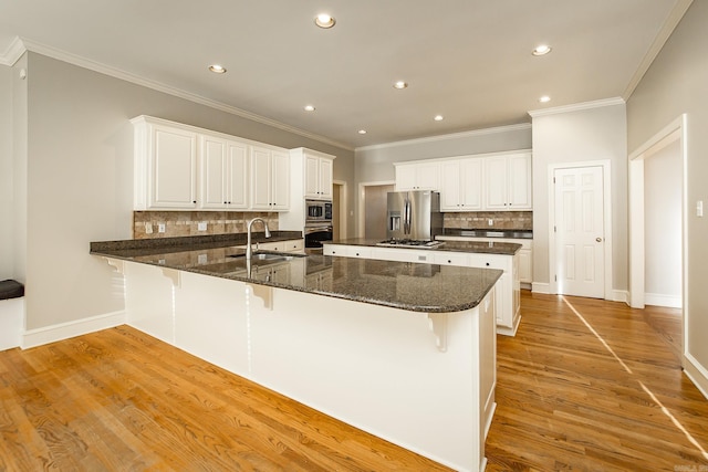 kitchen featuring a kitchen bar, sink, light hardwood / wood-style flooring, stainless steel appliances, and white cabinets