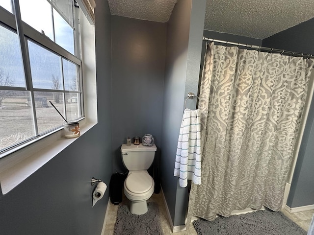 bathroom with a shower with curtain, toilet, and a textured ceiling