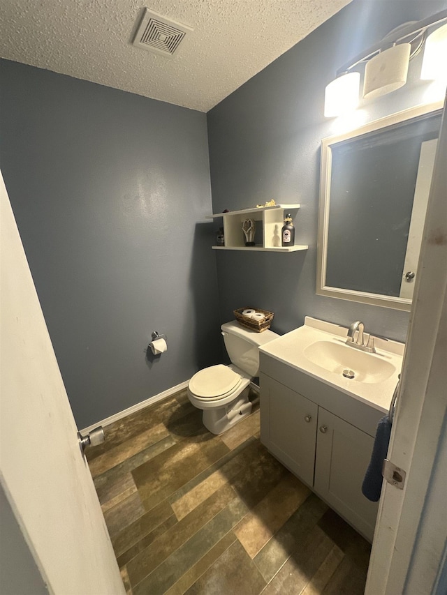 bathroom featuring hardwood / wood-style flooring, vanity, toilet, and a textured ceiling