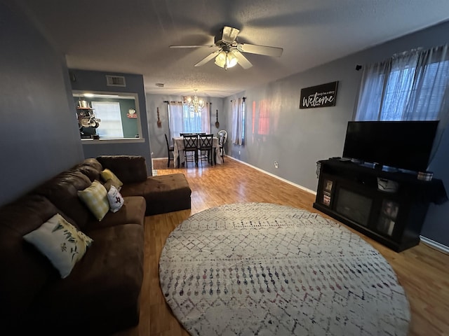 living room with ceiling fan with notable chandelier, hardwood / wood-style floors, and a textured ceiling