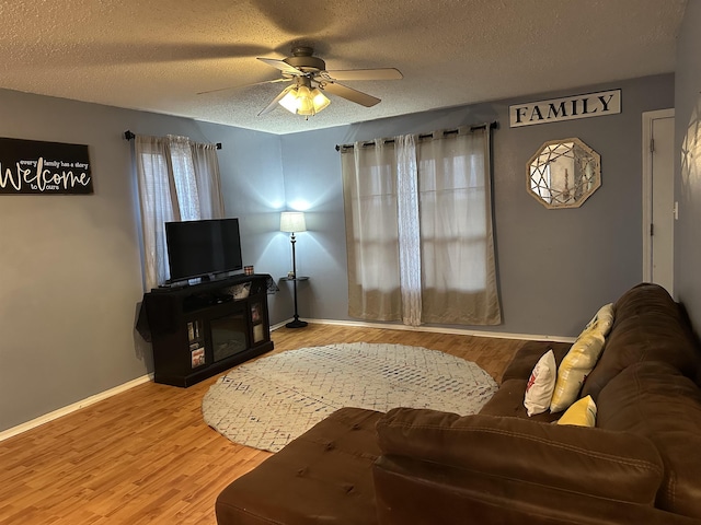 living room featuring ceiling fan, wood-type flooring, and a textured ceiling