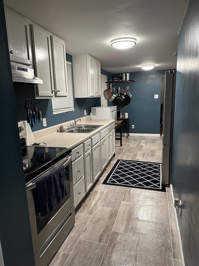 kitchen with stainless steel electric range oven, sink, and white cabinets