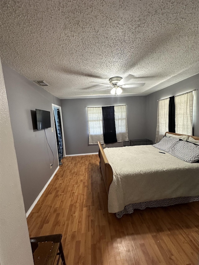 bedroom with ceiling fan, hardwood / wood-style floors, and a textured ceiling