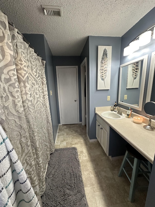 bathroom with vanity, a shower with shower curtain, and a textured ceiling