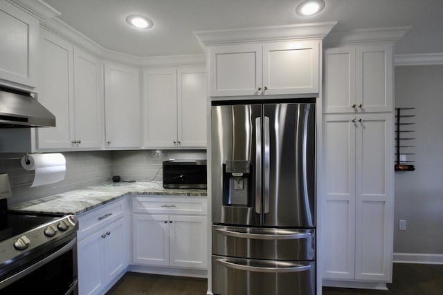 kitchen with appliances with stainless steel finishes, tasteful backsplash, white cabinets, light stone counters, and dark wood-type flooring