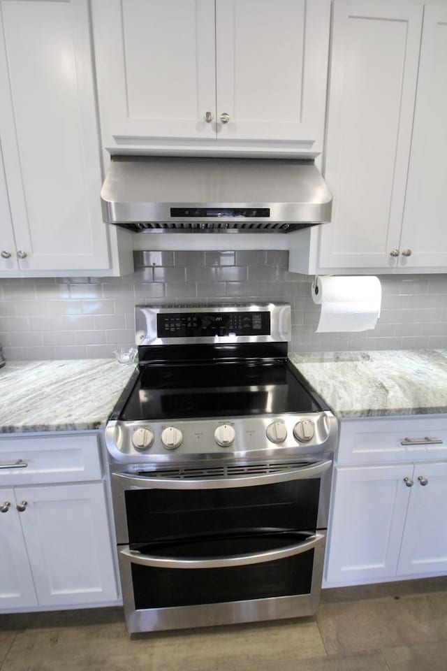 kitchen with tasteful backsplash, double oven range, range hood, and white cabinets