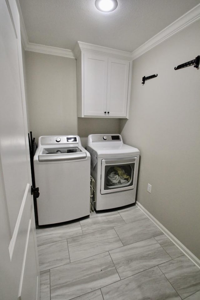 laundry area featuring crown molding, a textured ceiling, cabinets, and washing machine and clothes dryer