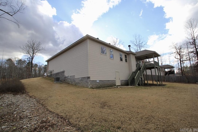 view of property exterior featuring a wooden deck, a yard, and central air condition unit