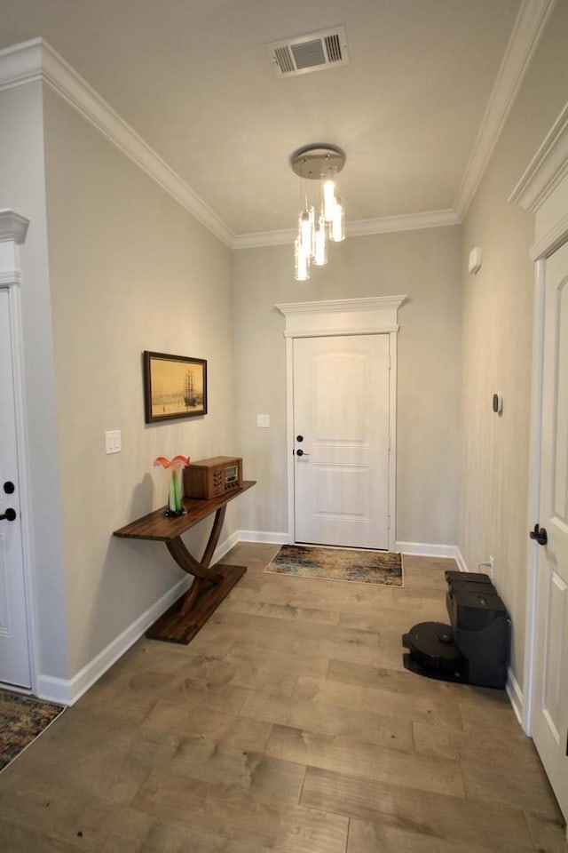 foyer entrance featuring hardwood / wood-style flooring, ornamental molding, and a chandelier