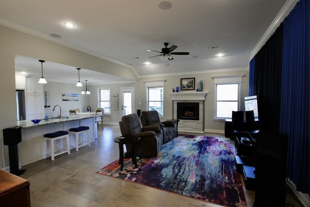 living room with sink, ornamental molding, and ceiling fan