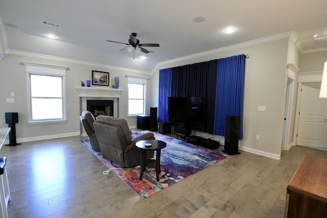 living room featuring ceiling fan, a healthy amount of sunlight, wood-type flooring, and ornamental molding