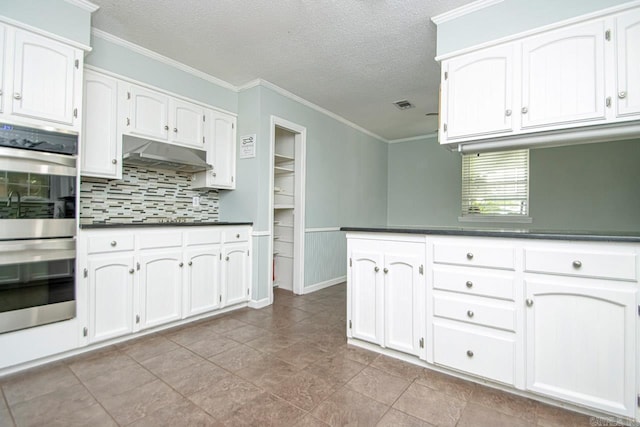 kitchen with white cabinetry, stainless steel double oven, ornamental molding, and a textured ceiling