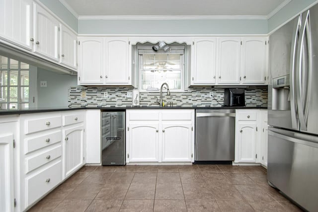 kitchen featuring appliances with stainless steel finishes, sink, white cabinets, decorative backsplash, and crown molding