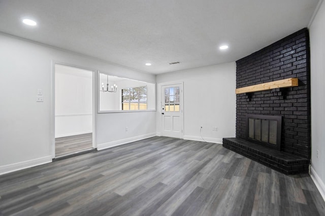 unfurnished living room featuring a notable chandelier, a fireplace, dark hardwood / wood-style floors, and a textured ceiling