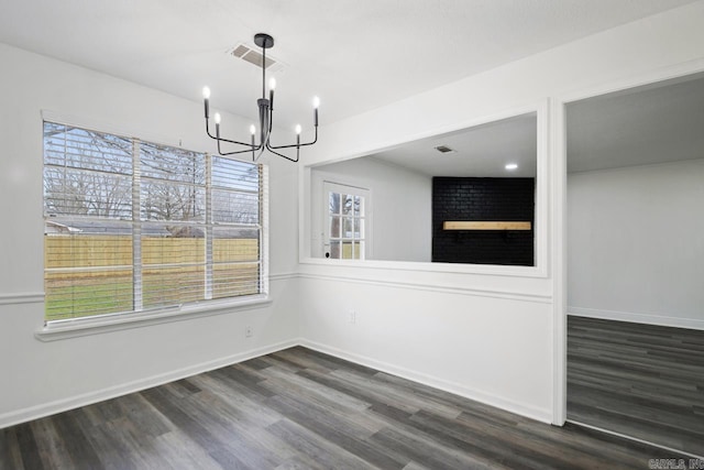 unfurnished dining area featuring an inviting chandelier and dark hardwood / wood-style flooring