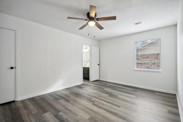 spare room with dark hardwood / wood-style flooring, ceiling fan, and a textured ceiling