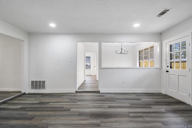 unfurnished dining area featuring a textured ceiling, dark wood-type flooring, and a chandelier