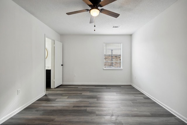 empty room with ceiling fan, dark wood-type flooring, and a textured ceiling